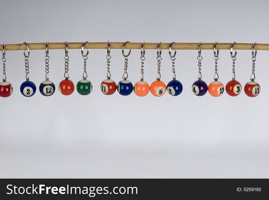 A number of pool balls miniaturized and attached to keyrings and hanging off a stick. A number of pool balls miniaturized and attached to keyrings and hanging off a stick.