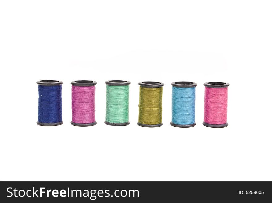 A row of colorful threads on spools isolated on white. A row of colorful threads on spools isolated on white