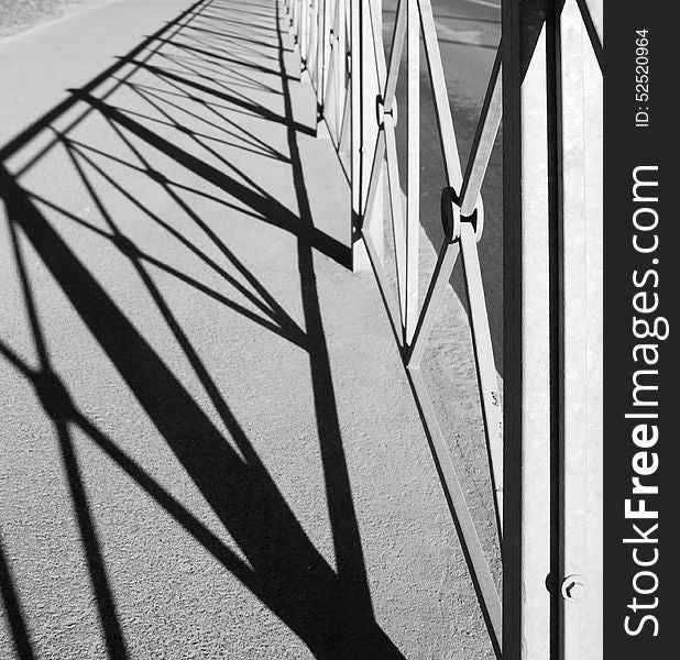 Geometric pattern with shadow of the metal fence outside black and white