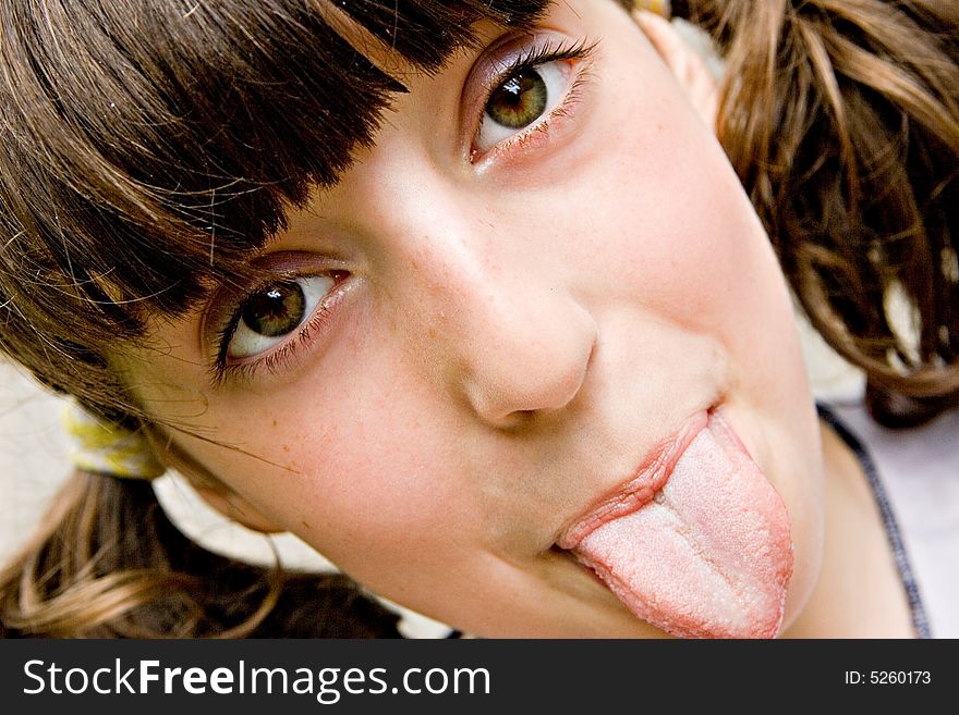 The brown-eyed dark-haired girl-teenager looks directly in a shot and puts out the tongue. The brown-eyed dark-haired girl-teenager looks directly in a shot and puts out the tongue