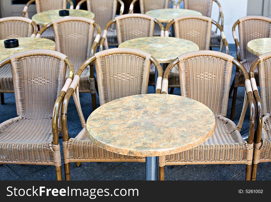 Empty wicker chairs with little tables in a sunny day