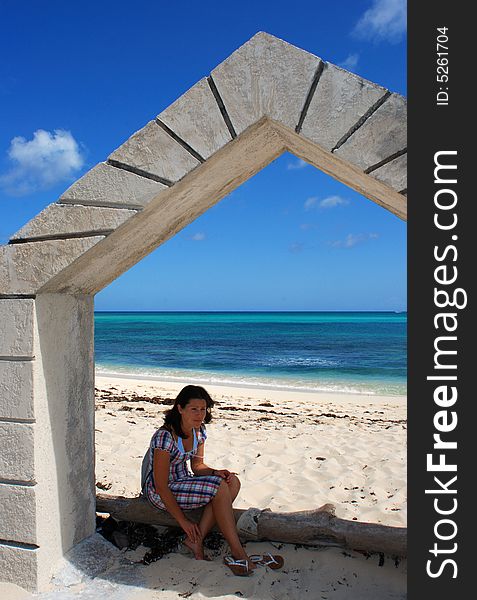 The girl sitting in the shadow of an arch, the entrance to Sandyport beach in Nassau, The Bahamas. The girl sitting in the shadow of an arch, the entrance to Sandyport beach in Nassau, The Bahamas.