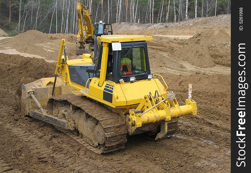 Bulldozer at work with wooden background