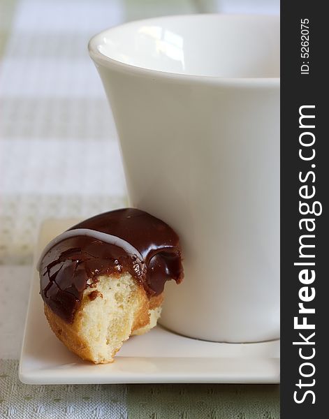 Chocolate iced donut with a cup and saucer. Chocolate iced donut with a cup and saucer.