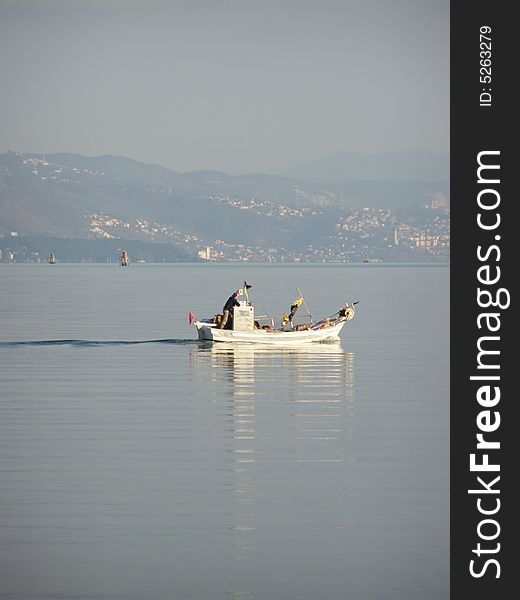 Fisherman in boat sailing out, Gulf of Triest, Italy Coastline, view of Miramare Castle and Trieste lighthouse