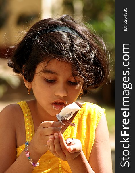 A girl absorbed in eating the ice-cream. A girl absorbed in eating the ice-cream.