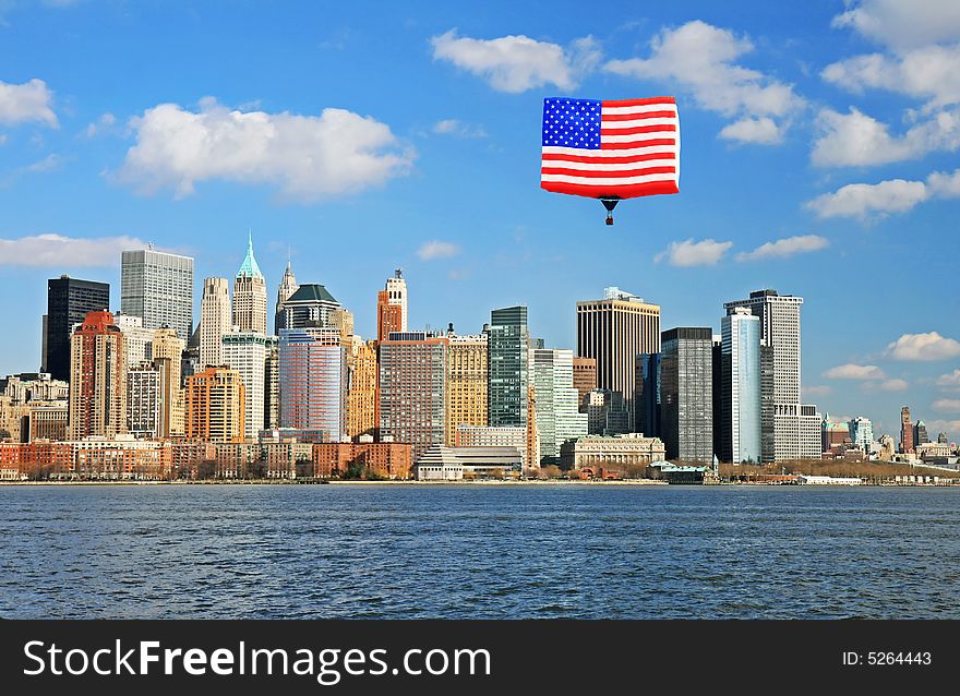 The Lower Manhattan Skyline viewed from Liberty Park. A hot air balloon shaped like the American flag flies overhead.