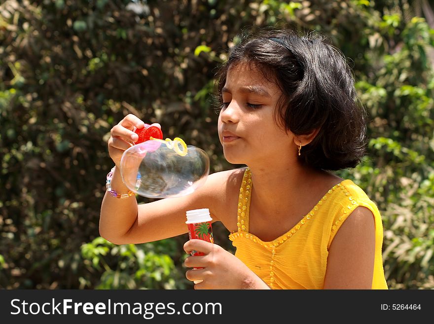 A girl making her hard efforts to blow the bubble. A girl making her hard efforts to blow the bubble.