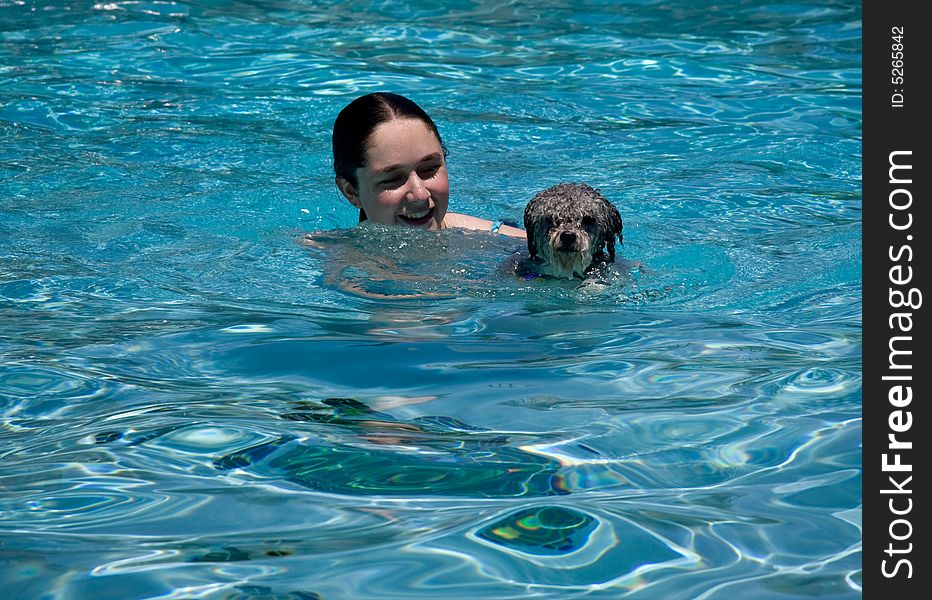 Girl and small puppy swimming in a blue swimming pool. Girl and small puppy swimming in a blue swimming pool