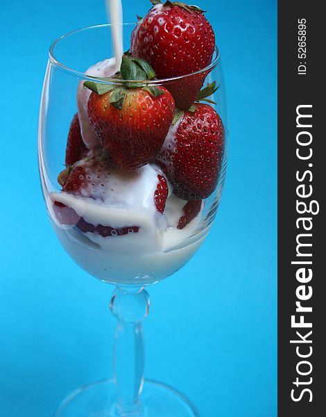 Preparing Strawberry milkshake in crystal glass with blue background