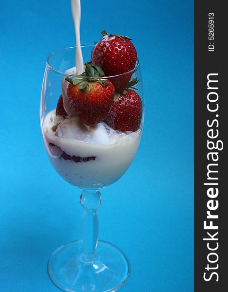 Preparing Strawberry milkshake in crystal glass with blue background