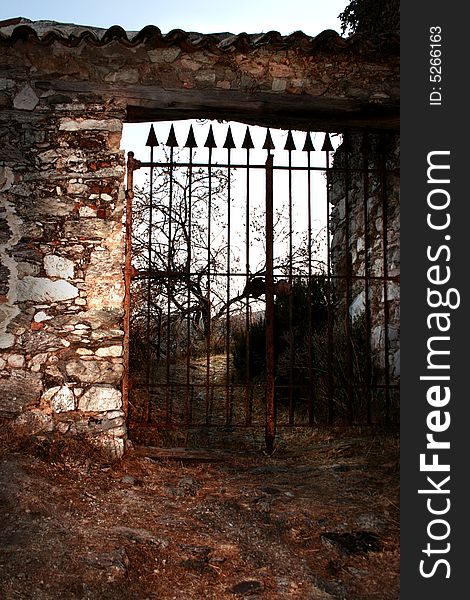 An old gate closing an abandoned cemetery surrounded by a stone wall. An old gate closing an abandoned cemetery surrounded by a stone wall