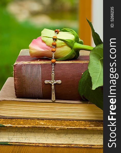 Religious still life with small cross, old book and rose