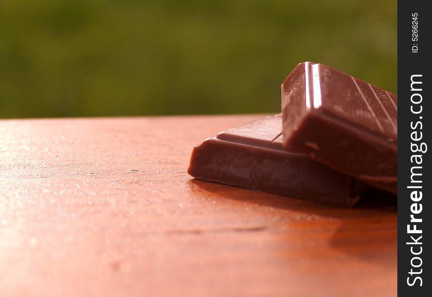 Two brick of chocolate on wooden bench.