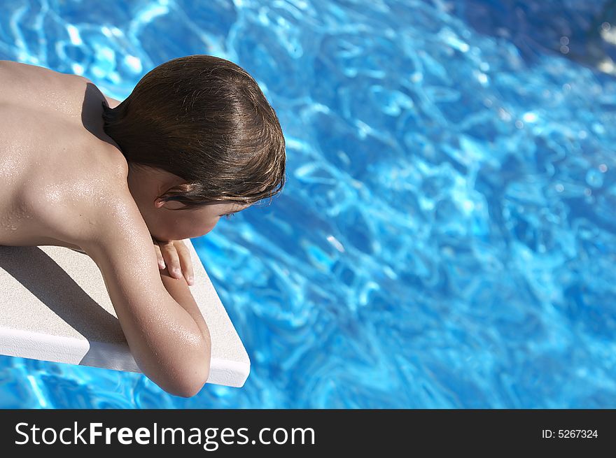 A boy looking into a pool from the diving board. A boy looking into a pool from the diving board