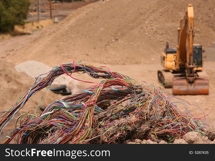 Closeup of a colorful bundle of old telephone wires that had been dug up by a trackhoe which is in the background. Closeup of a colorful bundle of old telephone wires that had been dug up by a trackhoe which is in the background.