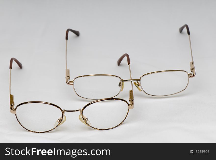Two pairs of spectacles or glasses with metal arms.