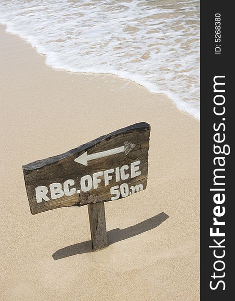 Wooden sign in sand near seashore