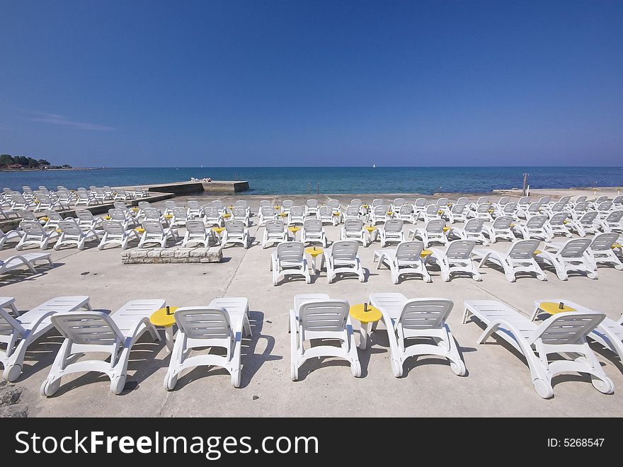 Plastic chairs rowed on a concrete terrace next to sea