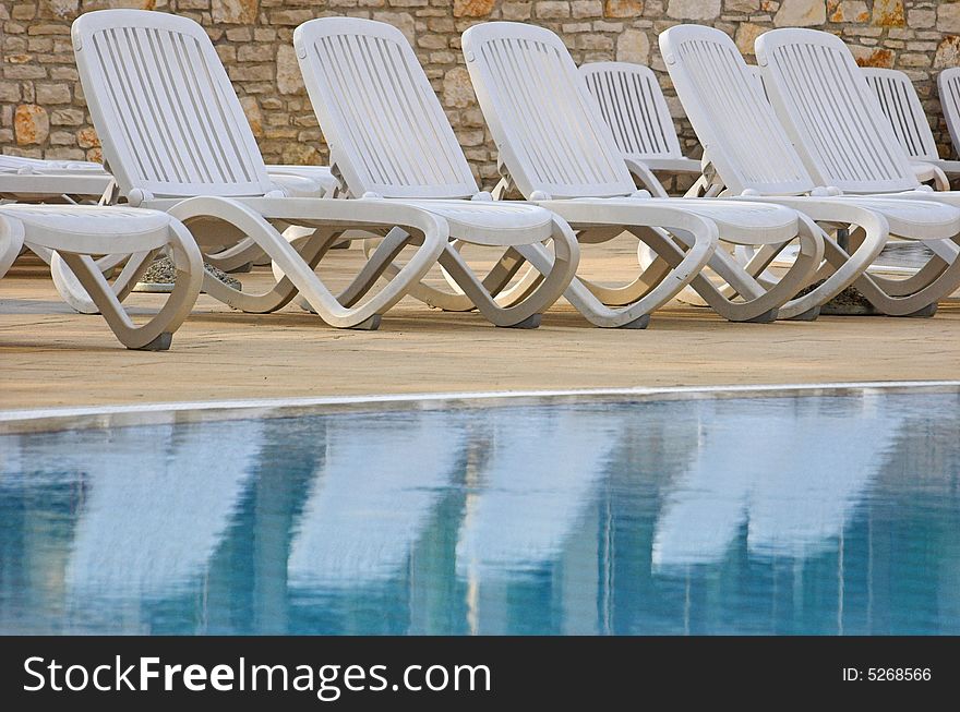 Plastic white chairs standing on a swimming pool terrace