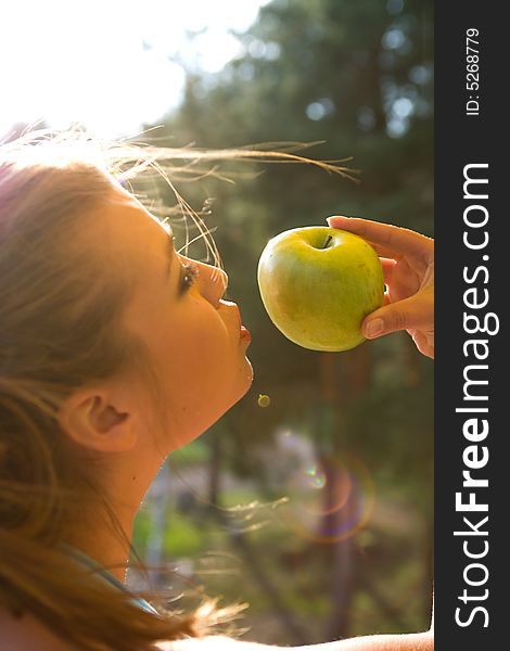 Girl with apple on sunset on green background