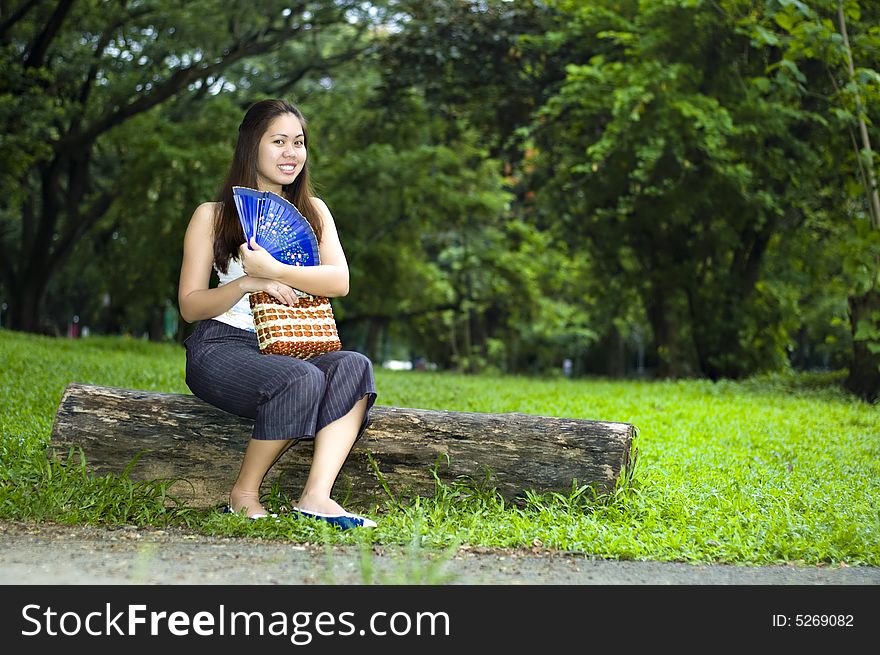 Happy Woman Sitting On Log With Blue Fan