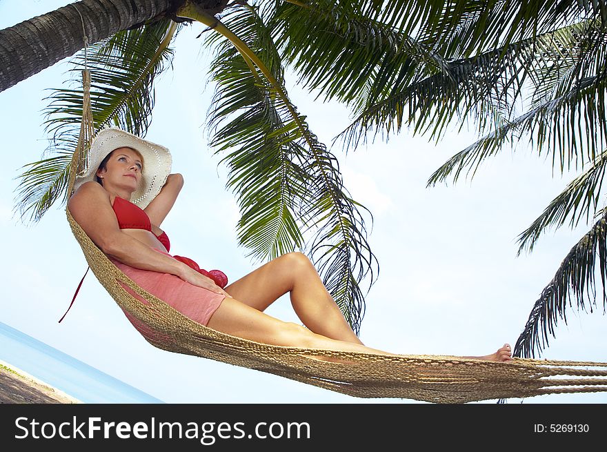 View of nice woman lounging in hammock in tropical environment