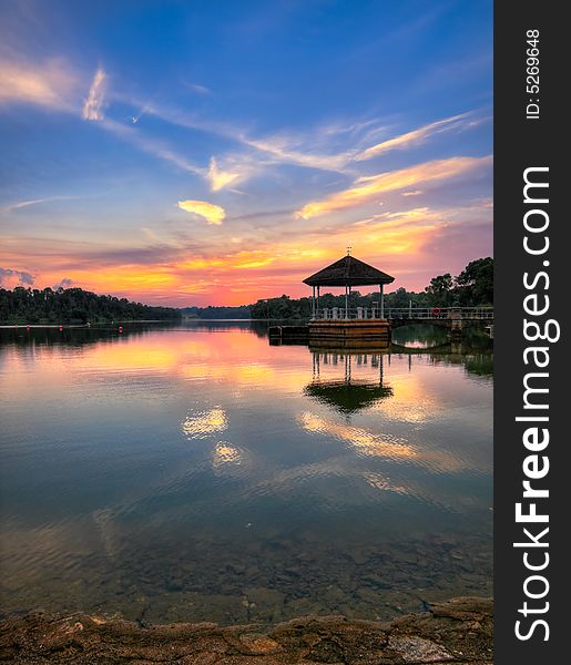 Sunset silhouetting a pavilion on a perfectly still lake. Sunset silhouetting a pavilion on a perfectly still lake