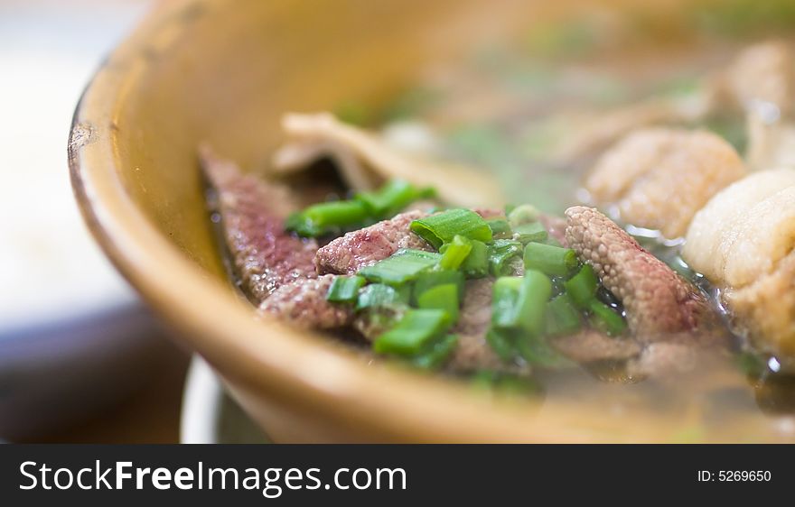 Asian dish of a herbal, tea flavored soup of pork ribs, liver and stomach, garnished with chopped spring onions, served steaming hot, and eaten with plain boiled rice, called bak kut teh in the local language. Asian dish of a herbal, tea flavored soup of pork ribs, liver and stomach, garnished with chopped spring onions, served steaming hot, and eaten with plain boiled rice, called bak kut teh in the local language