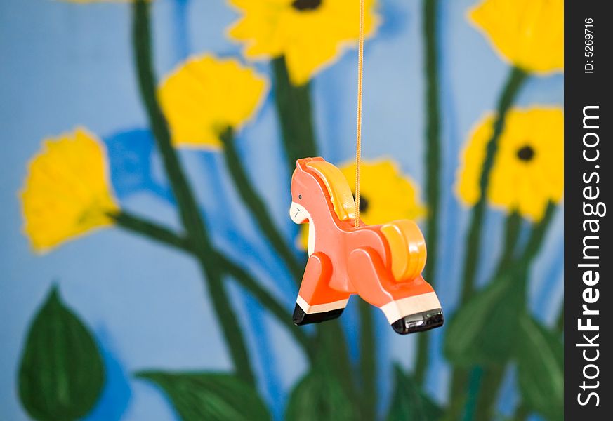 Plastic figurine of an orange horse on a mobile against a colorful painted background. Plastic figurine of an orange horse on a mobile against a colorful painted background
