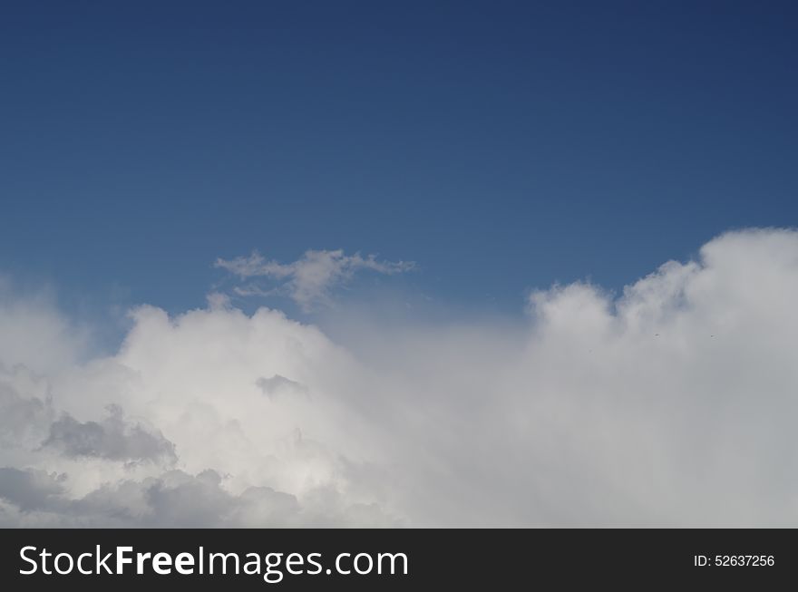 White and grey  fluffy clouds in the blue sky. Clouds are taking half of frame. White and grey  fluffy clouds in the blue sky. Clouds are taking half of frame