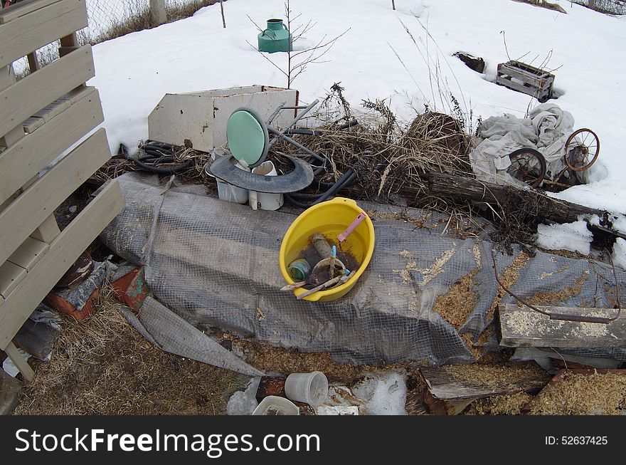 Yellow plastic basin of water, brushes and rusty paint roller on backyard. Mess on backyard.