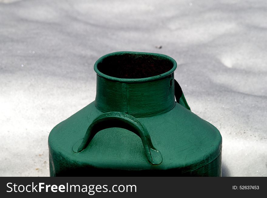 Old large milk cans painted in green color in the snow. Closeup. Isolated. Old large milk cans painted in green color in the snow. Closeup. Isolated.