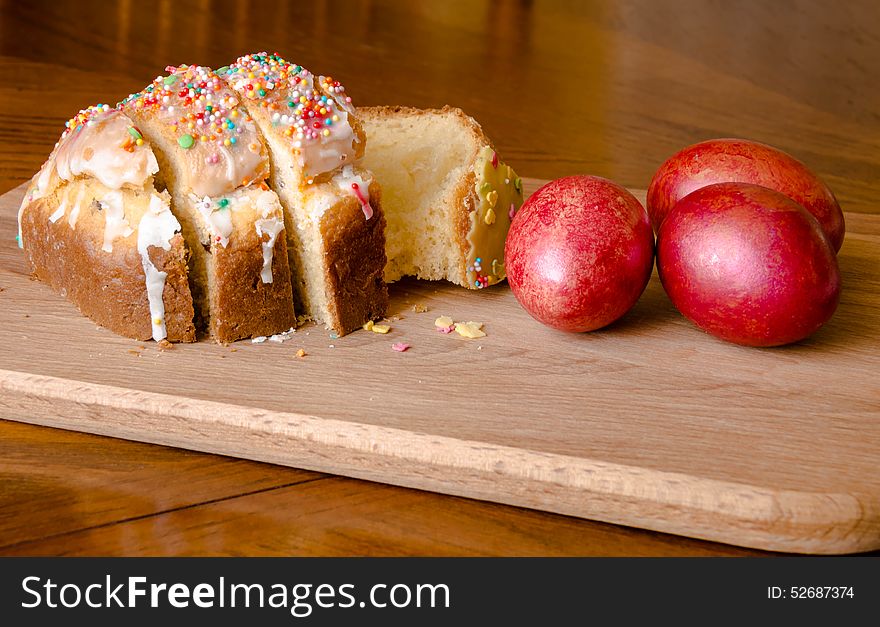 Easter cake and red eggs on a wooden board