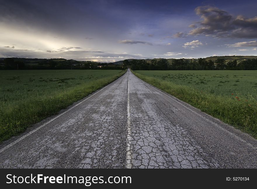 Countryside road going in the horizon at sunset