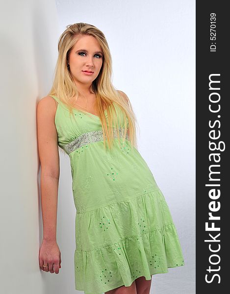 Beautiful teen girl model wearing a green dress on a neutral background