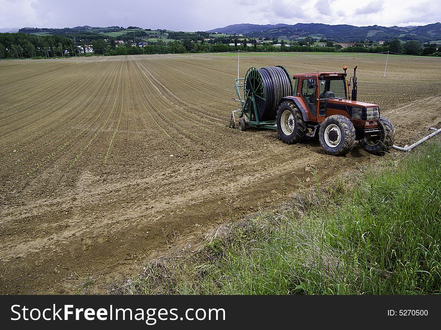 A tractor on a farm with haybales behind.