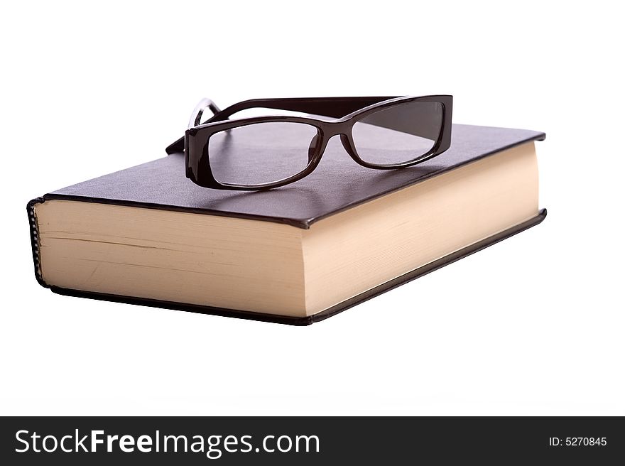 A pair of fashionable reading glasses on top of a blck book on a white background with copy space. A pair of fashionable reading glasses on top of a blck book on a white background with copy space