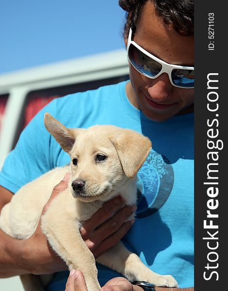 Young man holding his labrador puppy. Young man holding his labrador puppy