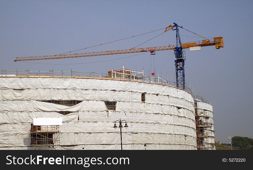 Overview of building site as construction taking place with crane.