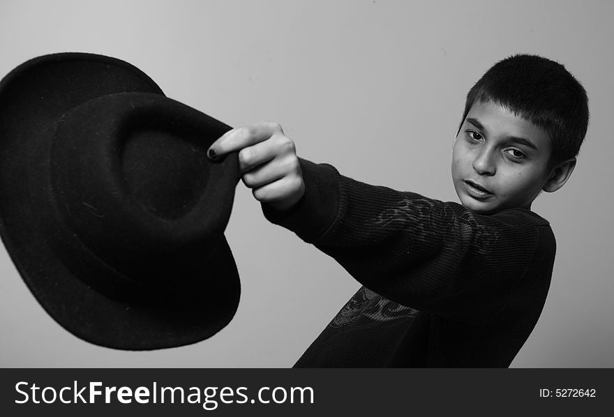 Young boy holding out a black hat. Young boy holding out a black hat