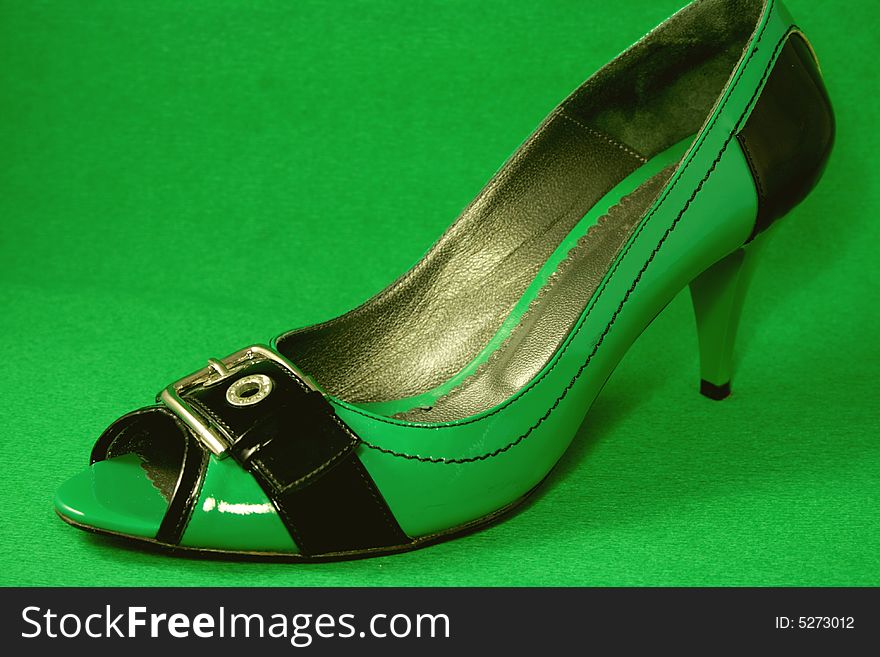 Green High-heeled shoe close-up on Green background. Series