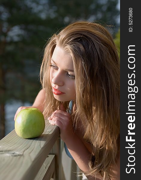 Girl with apple on sunset on green background