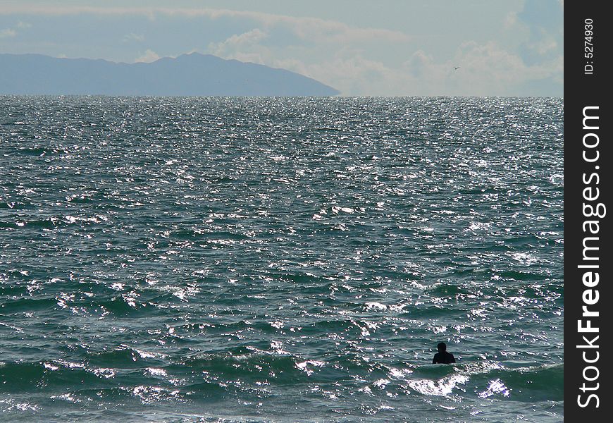 A lone swimmer off the coast of Newport Beach California contemplates Santa Catalina Island