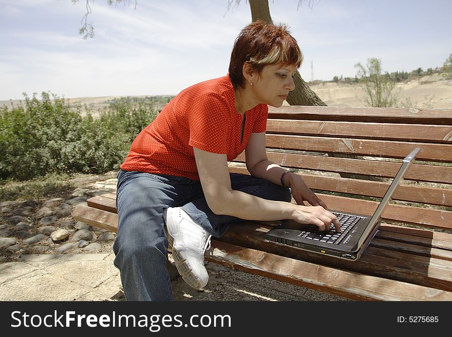 A young woman using a portable computer outside. A young woman using a portable computer outside