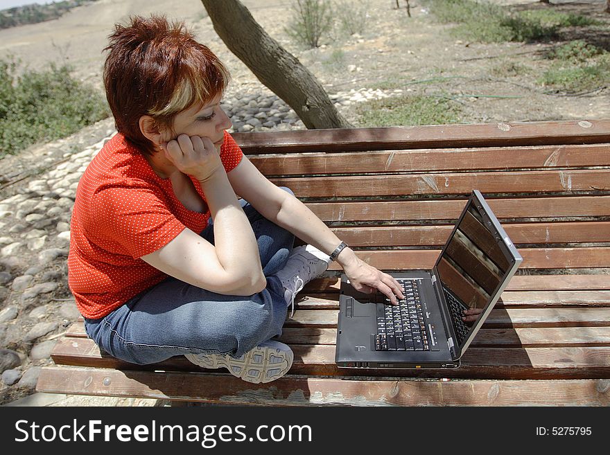 A young woman using a portable computer outside. A young woman using a portable computer outside