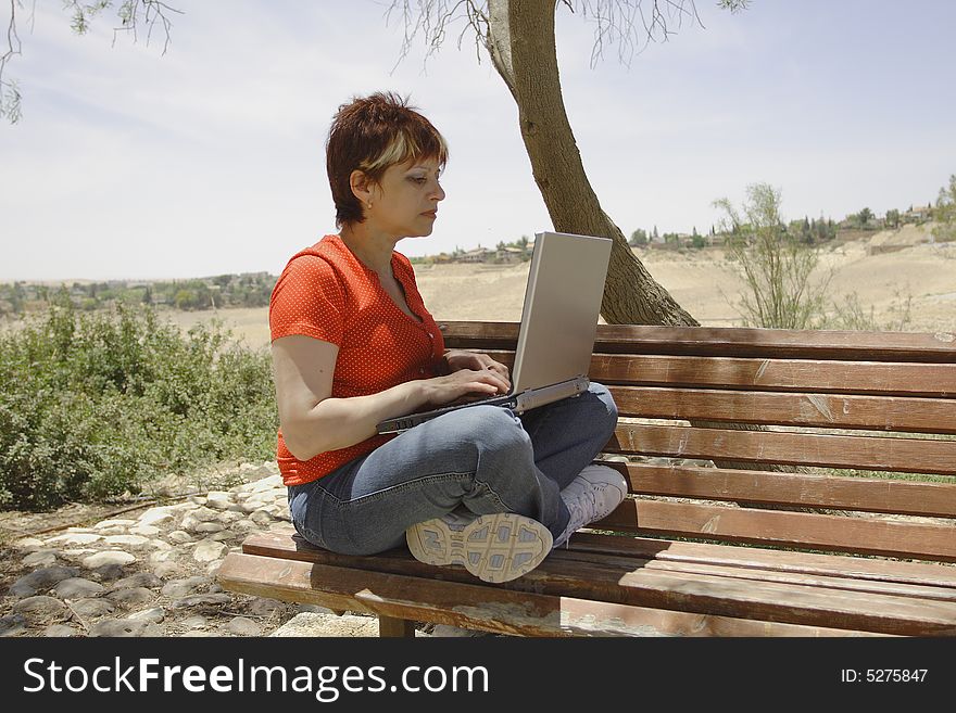 A young woman using a portable computer outside. A young woman using a portable computer outside