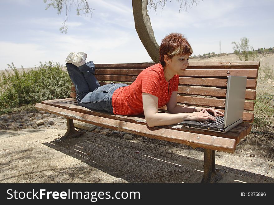 A young woman using a portable computer outside. A young woman using a portable computer outside