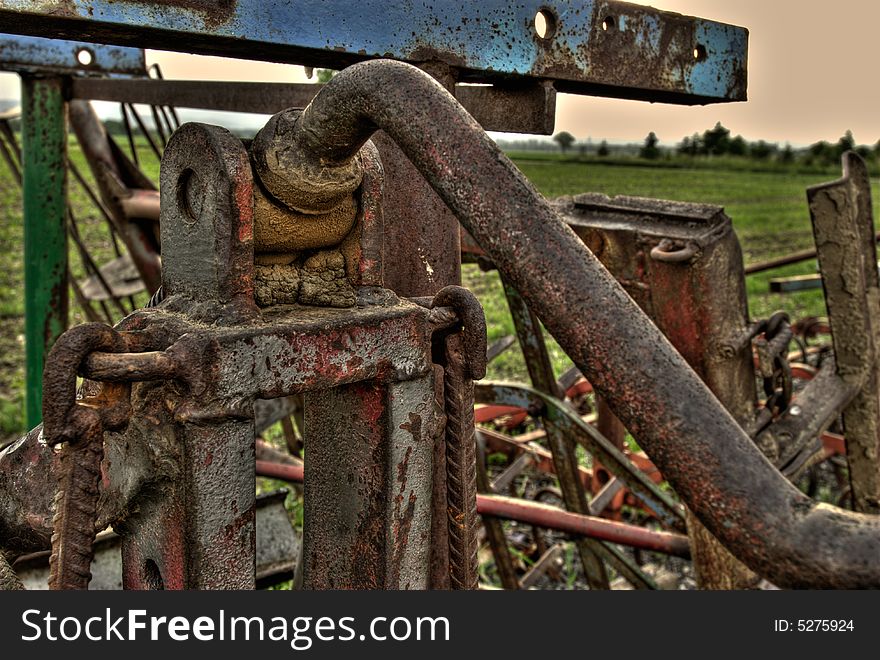 Detail of a farm machine in front of a grain field in HDR