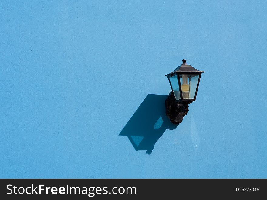 A metal street lamp on a blue wall